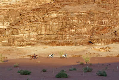 Trois cavaliers galopant dans le Wadi Rum