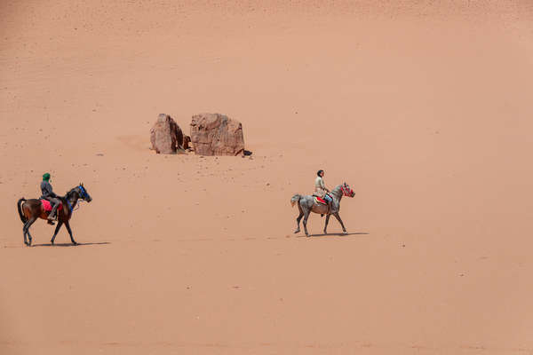 Deux cavaliers et un cube de pierre dans le désert