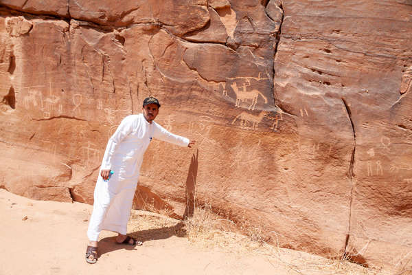 Guide saoudien devant des gravures rupestres à Sharaan
